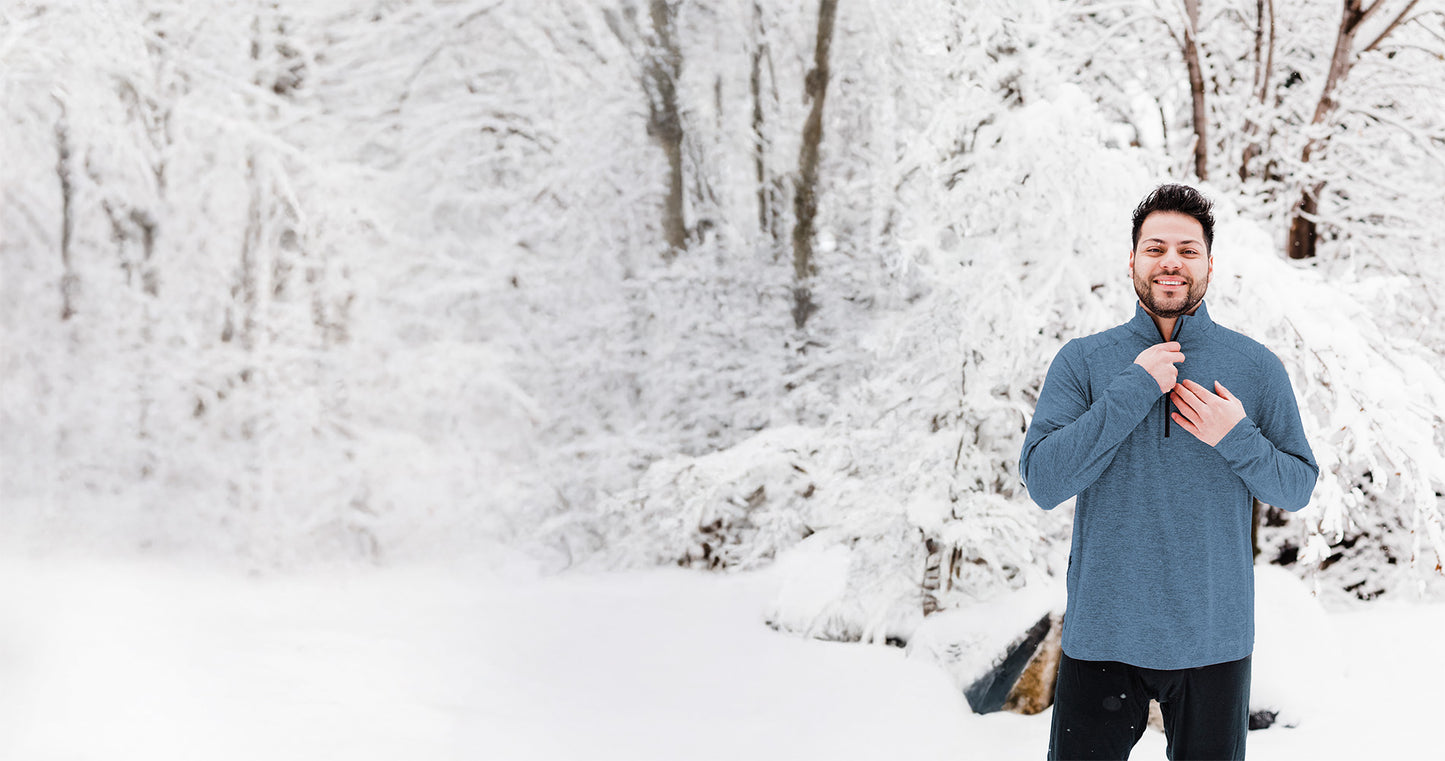 Man in a blue sweater standing in a snowy forest