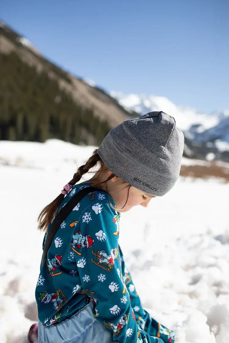 Youth wearing colorful Hot Chillys thermal base layers and gray beanie in snowy mountains