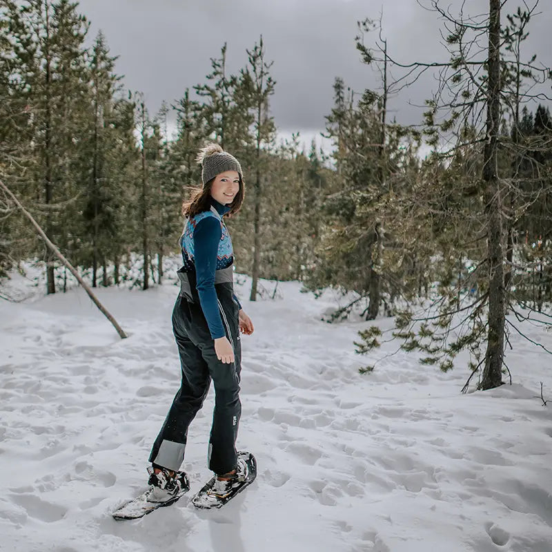 Person snowshoeing through a snowy forest