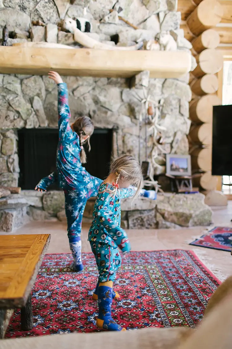 Kids wearing Hot Chillys thermal base layers, playing indoors in a cozy cabin