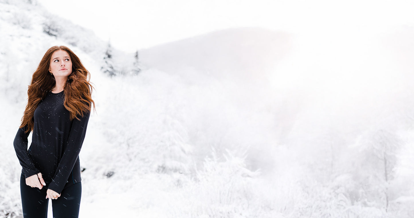 Woman in a black outfit standing in a snowy landscape