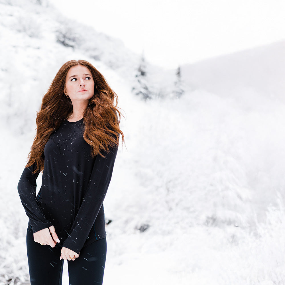 Woman in a black outfit standing in a snowy landscape