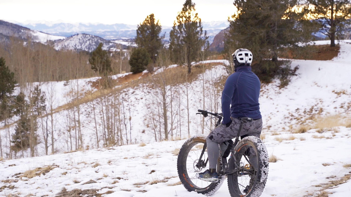 Rider wearing Hot Chillys Micro Elite XT base layer mountain biking in snow